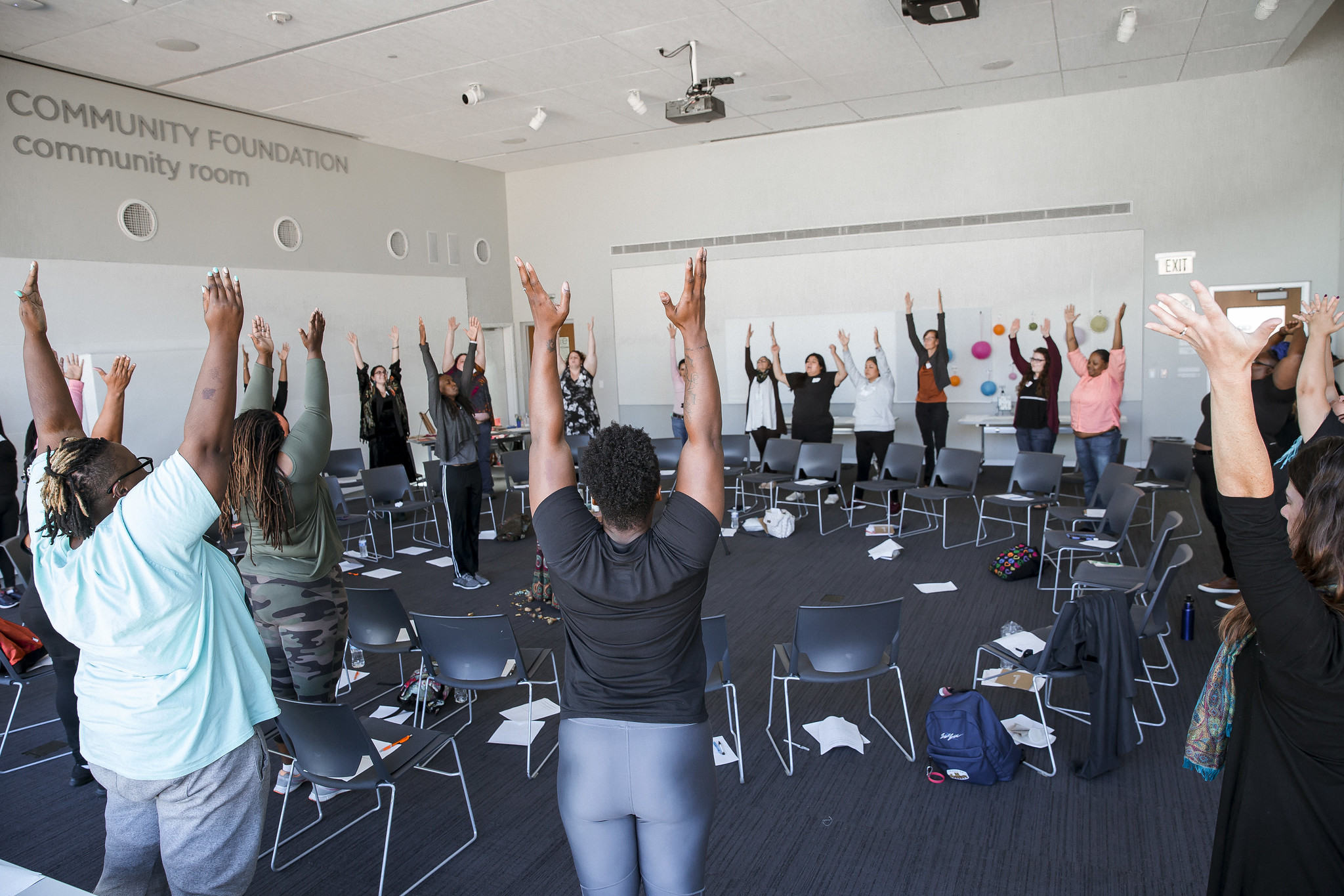 Group of people standing in a circle with their hands raised