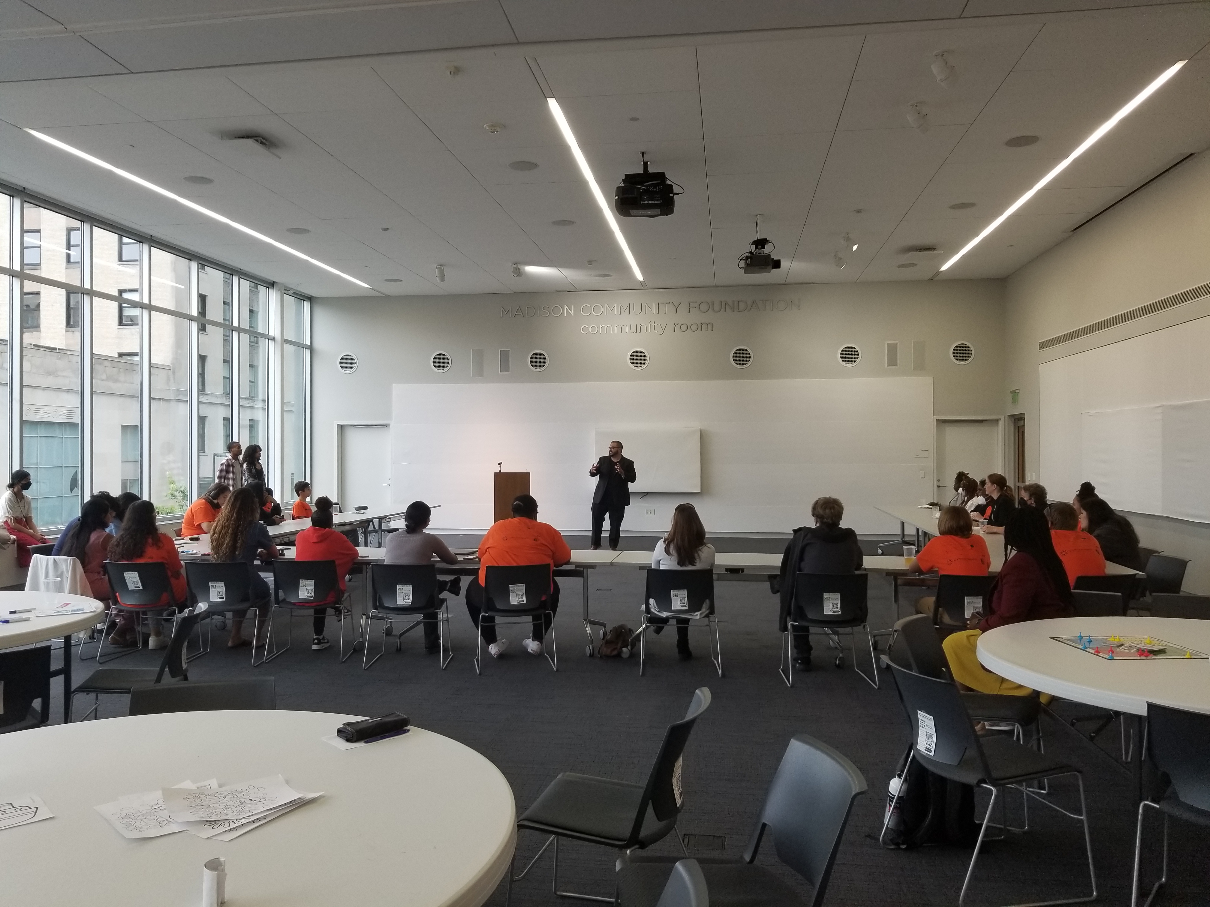 Students sitting at tables set in a U Shape facing a speaker