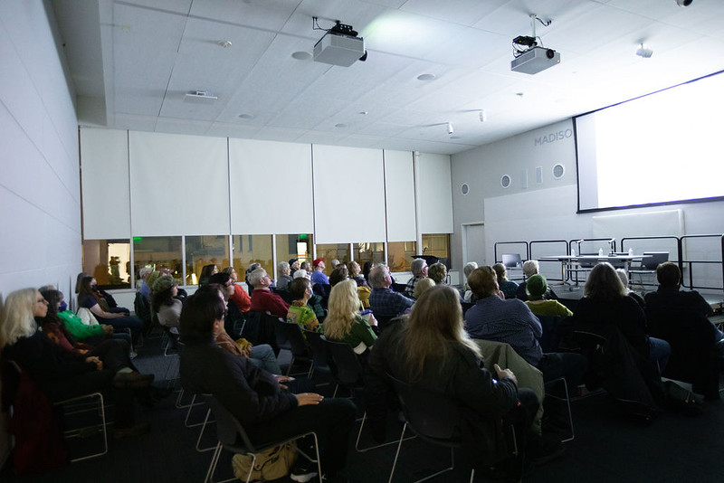 Group of people sitting in rows and watching a large screen