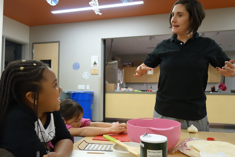 Chef Lily laughs with a student while she teaches her cooking class