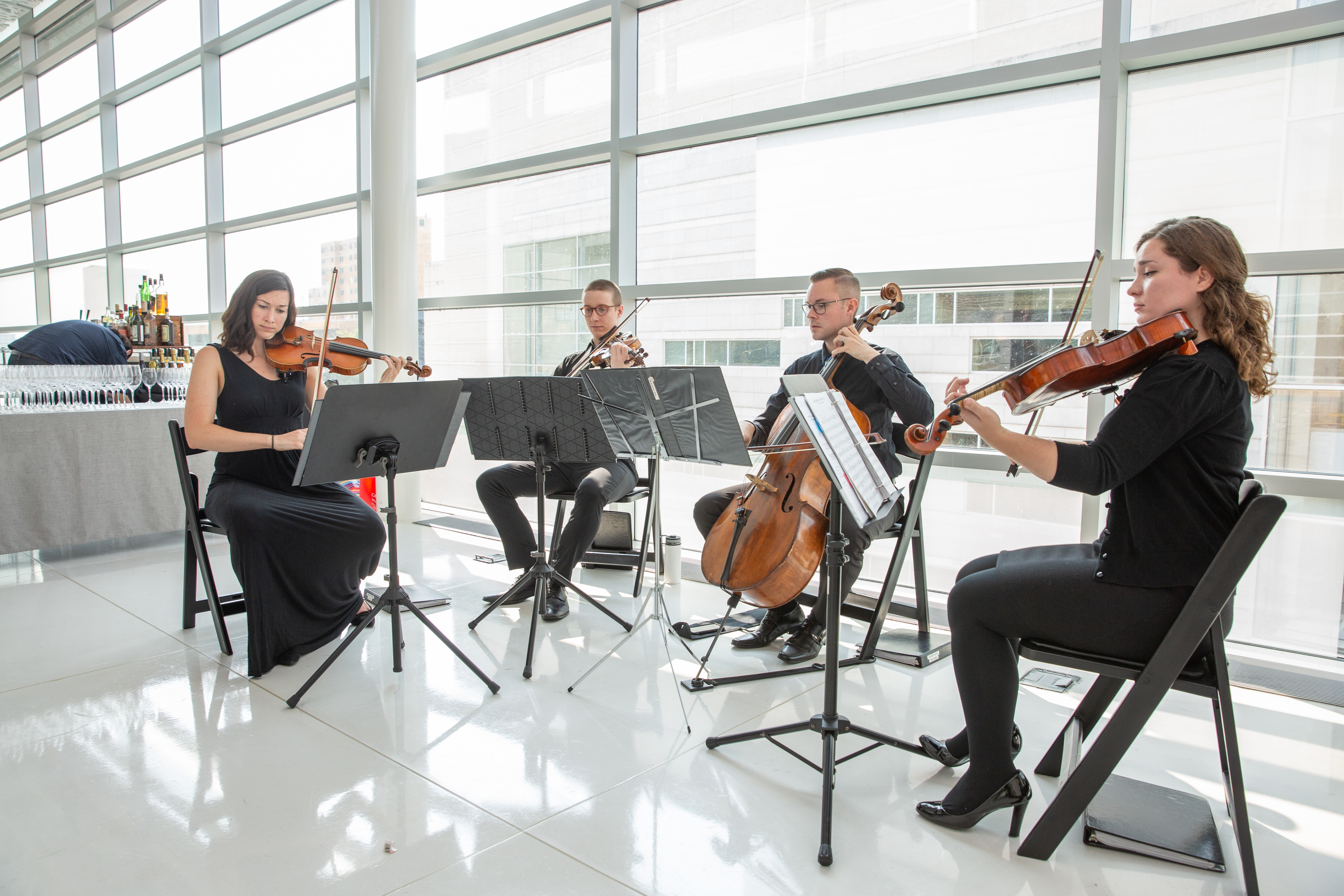 four piece string band playing in front of windows