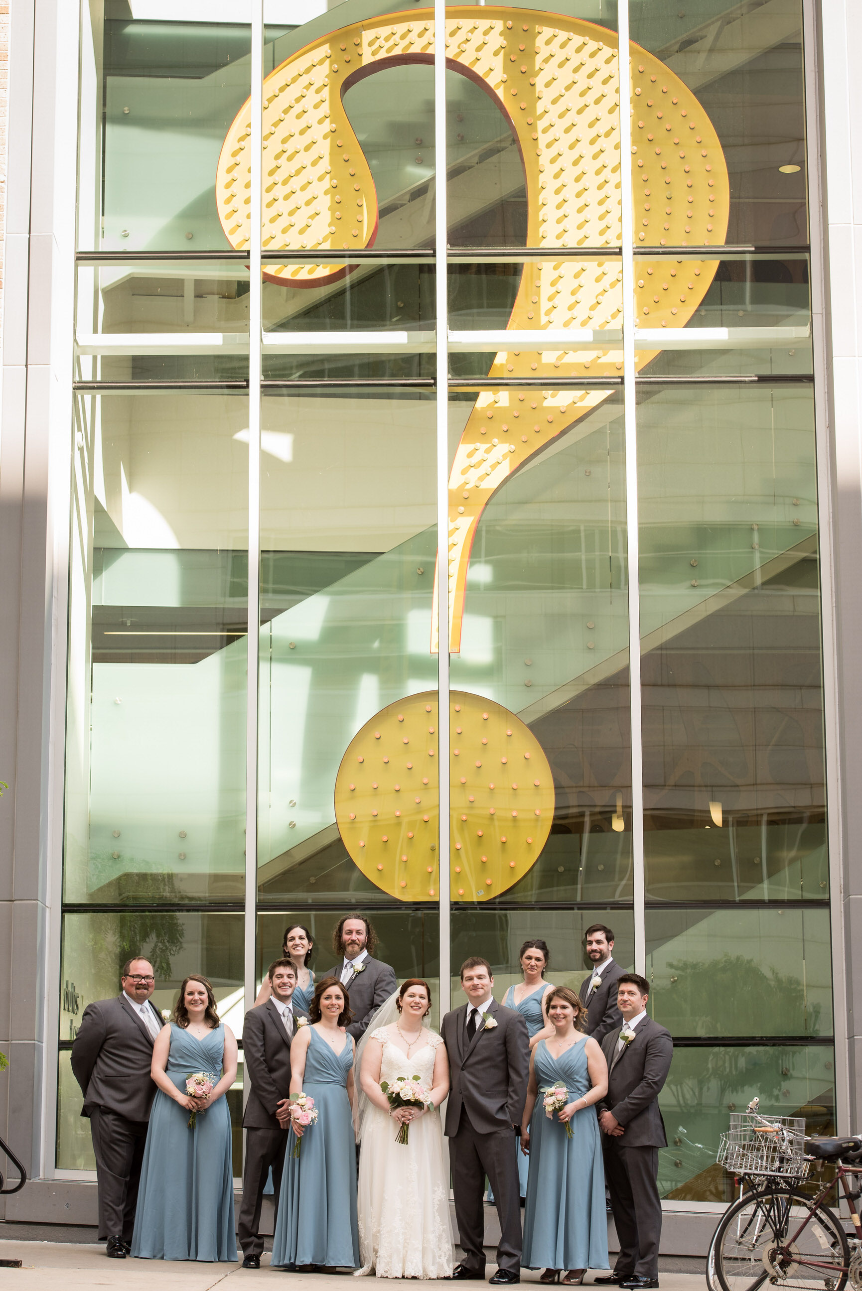 Wedding party standing in front of a giant question mark