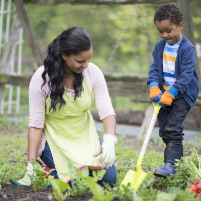 A mother and her young son work together in a garden