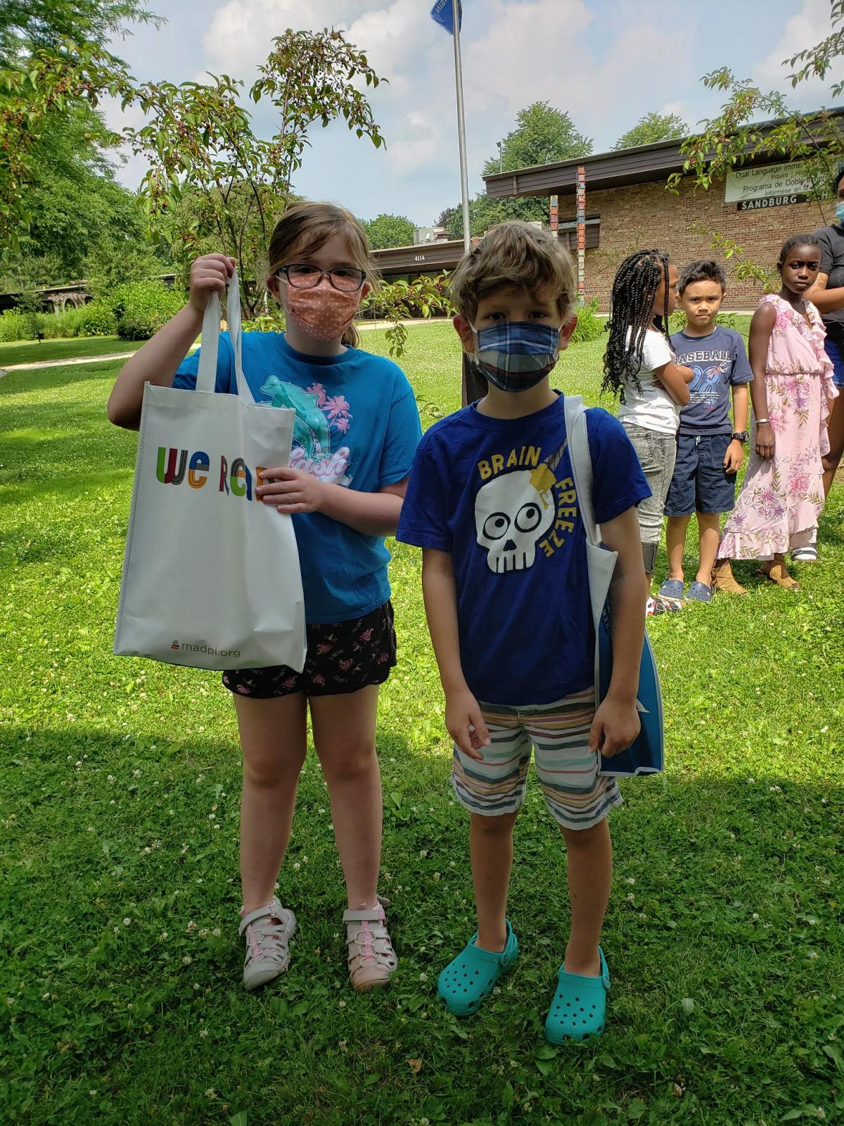 Two masked students at Sandburg Elementary get their books 