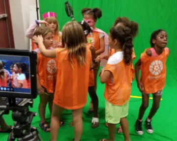 group of kids recording a music video at the library in front of a green screen