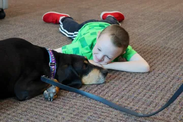 Little kid laying next to a dog at the library 